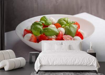 A view of caprese salad with tomato, mozzarella, basil and olive oil on white plate. Creative isometric style. Mediterranean cuisine. Wall mural