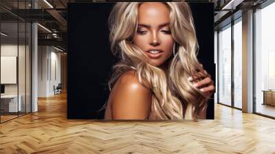 Beautiful blond tanned woman with wavy hair posing on black background Wall mural