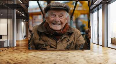 Funny and smiling elderly man of about 90 has fun on the swing, radiating joy and happiness Wall mural