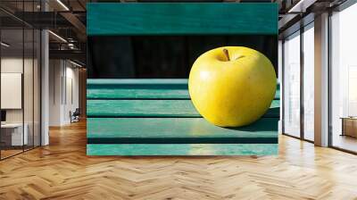 One yellow apple on a green background. Fresh healthy fruit (apple) laying on a contrasting green striped bench. Healthy food, organic or vegetarian concept. Last apple in the shop. Wall mural