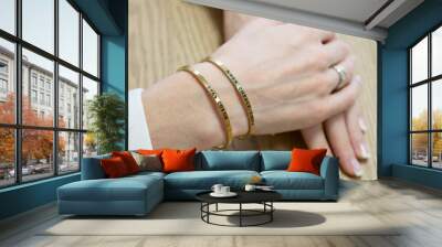 Womans hands with two thin gold bracelets. The inscription on the bracelet in Russian Live, laugh, love, be yourself. Simple jewelry with printed inscription. Wall mural