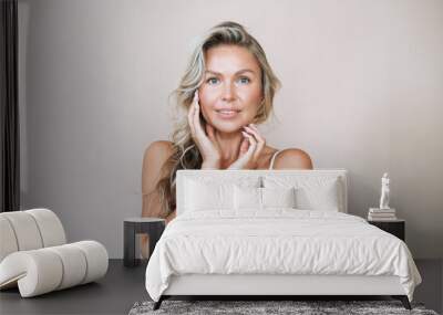 Beauty portrait of blonde hair smiling young woman isolated on beige background Wall mural