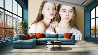 Fashion beauty models two sisters twins beautiful nude girls looking at the camera isolated on beige background Wall mural