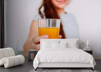 The girl holding glass of orange juice in hand, selective focus Wall mural