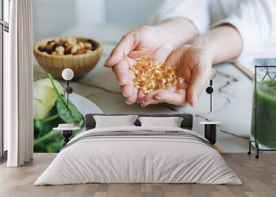 Woman doctor nutritionist hands in white shirt with omega 3, vitamin D capsules with green vegan food. The doctor prescribes a prescription for medicines and vitamins at the clinic Wall mural