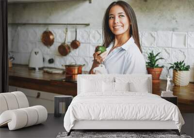 Young asian woman in white shirt hold knitted rag bag shop with green apples in hands on kitchen Wall mural