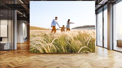 A hipster family walks in a summer field. Wall mural