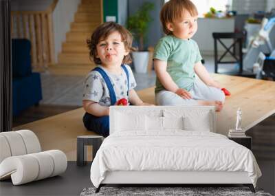 Little brothers eat strawberries are sitting on a wooden table in the kitchen. Wall mural