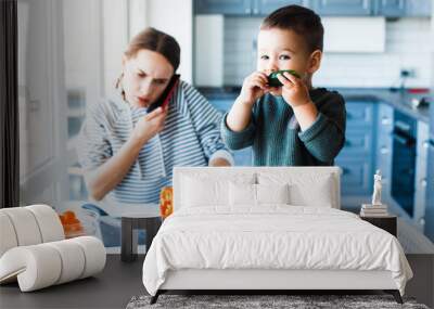 Young mother with her child in a modern kitchen setting. Young attractive cook woman desperate in stress, tired. Wall mural