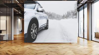 Suv car with rooftop cargo carrier trunk stay on roadside of winter mountain road in snowy blizzard. Family trip to ski resort. Winter holidays adventure. car on winter road Wall mural