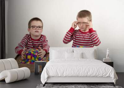 Funny children play scammers. Cute little kid boy in colorful clothes. Fraudulent game of a thimble. 1 april fool day. The shell game (also known as thimblerig, three shells and a pea). Copy space. Wall mural