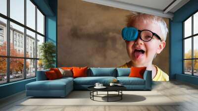 Portrait of funny child in new glasses with patch for correcting squint .Ortopad Boys Eye Patches nozzle for glasses for treatment of strabismus (lazy eye) Wall mural