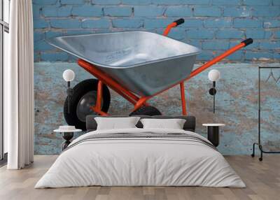 Wheelbarrow for garden construction on two wheels against background of brick wall Wall mural