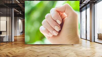 Broken nail on a woman's hand with a manicure on a green background Wall mural