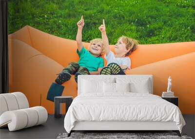 Two cute boys resting on an air sofa in the park. Wall mural