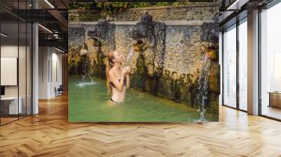 Young woman in hot springs banjar. Thermal water is released from the mouth of statues at a hot springs in Banjar, Bali, Indonesia Wall mural