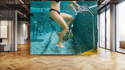 Young woman on bicycle simulator underwater in the pool Wall mural