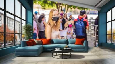 young woman wearing a hygiene protective mask over her face while walking at the crowded place. Healthcare and sickness prevention from coronavirus, Covid19 influenza in crowded place Wall mural