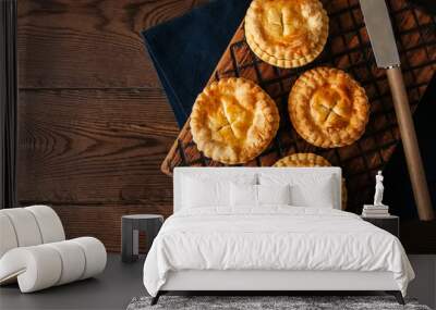 Mini meat pies from flaky dough on a wooden board over wooden background. Wall mural