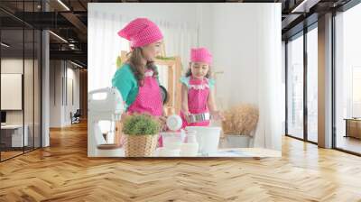 Beautiful asian mother and daughter wearing pink apron making cake in the kitchen. Wall mural