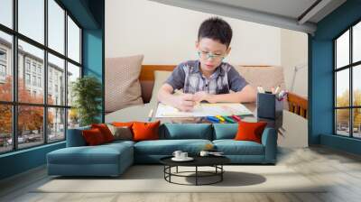 Young Asian boy at the table draw with color pencils Wall mural