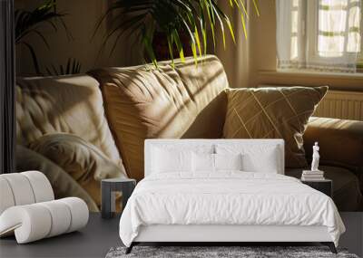 A beige sofa with two white pillows in the living room bathed in sunlight from an open window. The light creates long shadows on one side of the couch and plant leaves above it. Wall mural