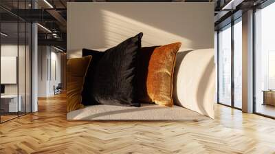 A close-up shot of three black, brown and mustard velvet cushions on the sofa in an elegant living room with white walls. The sunlight is shining through the window casting soft shadows over them. Wall mural