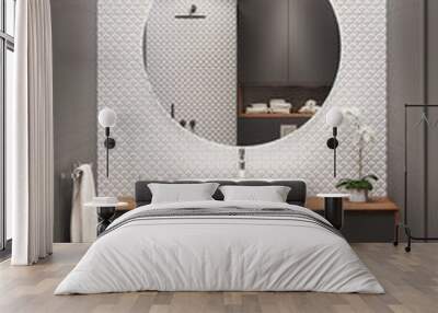 Black and white bathroom with a large round mirror on a white mosaic wall, an overhead washbasin on a wooden cabinet, an orchid, a towel, a rug on a wooden floor. 3d render Wall mural