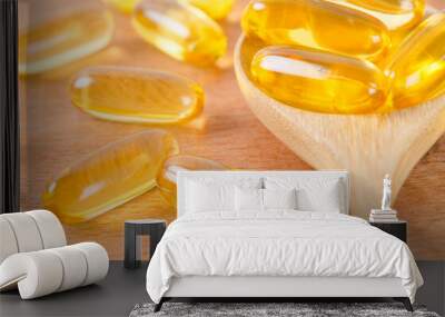 Cod liver oil omega 3 gel capsules on a spoon on wooden background. Wall mural