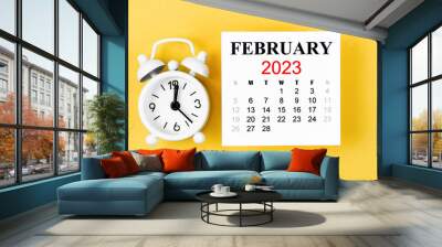 The February 2023 Monthly calendar for 2023 year with alarm clock on yellow background. Wall mural