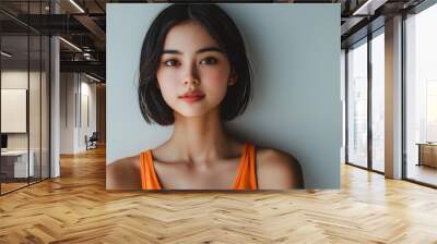 A Japanese woman in an orange tank top poses for a photograph, set against a white background in a studio portrait. She has a brown bob hairstyle, and the close-up,  Wall mural