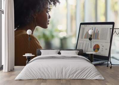 African American woman analyzing financial data on laptop screen Wall mural