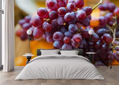 Closeup of a wooden bowl with ripe red grapes and raisins mandarins on kitchen table. Wall mural