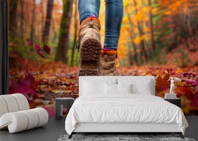 Person walking in autumn forest path with colorful fallen leaves and hiking boots Wall mural