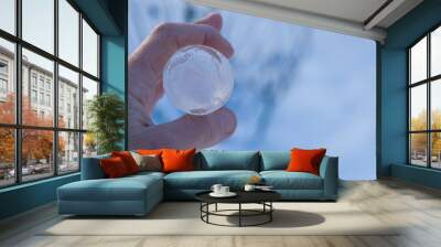 Pure transparent ice sphere in human hands on a blue background. Ecology concept. Copy space. Close up. Wall mural