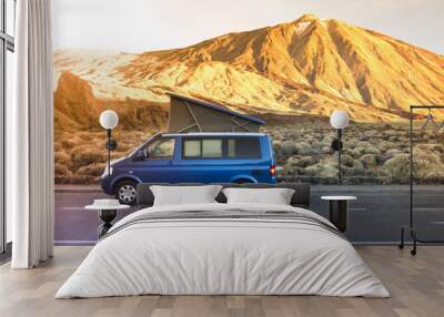 Small travel vehicle camping van or big car with folding rooftop with bed is parked under huge mountain formation. Tourism vacation and travel. Camper van and mountains landscape Wall mural