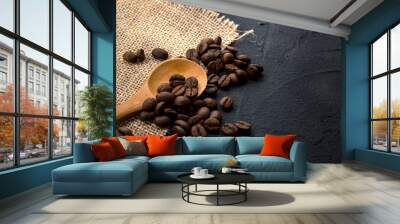 Coffee beans in burlap fabric and wooden spoon on dark cement background Wall mural