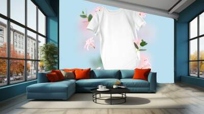 White cotton T-shirt floating on blue background. Conceptual composition of a blank unisex t-shirt and flowers in the air. Branding clothes front view. Mock up for design. clothing for men and women Wall mural