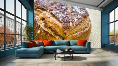 A loaf of sourdough bread freshly baked and standing on a mat ready to be sliced and eaten. Wall mural