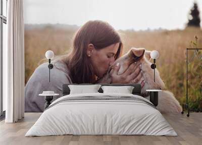 Human and a dog. Girl and her friend dog on the straw field background. Beautiful young woman relaxed and carefree enjoying a summer sunset with her lovely dog Wall mural