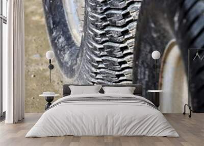 Close up of two tyres or tires on sandy mud, showing tread detail, one in focus and one in out of focus foreground Wall mural