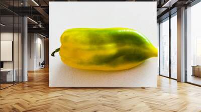 Yellow paprika with green spots on white table Wall mural