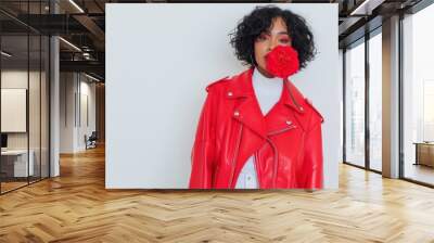 Fashionable woman in red leather jacket posing with flower in mouth on white background Wall mural