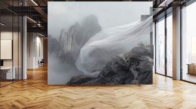 White satin scarf tied around weathered wooden cross on top of a windswept mountain peak overlooking a range of jagged, rocky peaks partially obscured by mist. Wall mural