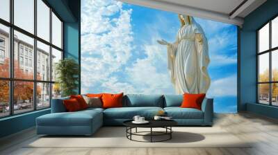 White statue of virgin mary standing with cloudy sky background Wall mural