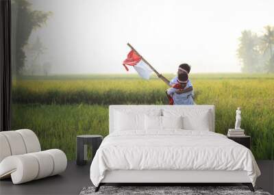  Two Indonesian elementary school students doing piggyback and walking while holding a flag during independence day in the rice field. Proud primary pupil with Indonesia flag  Wall mural