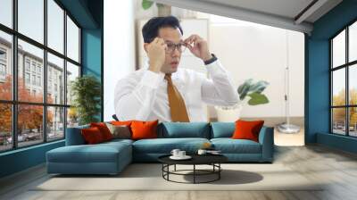 Asian Entrepreneur Thinking On Business Project While Holding Eyeglasses Sitting In Office.  Wall mural