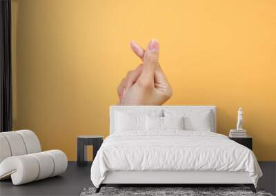 Female hand showing Korean mini heart from fingers over yellow background Wall mural