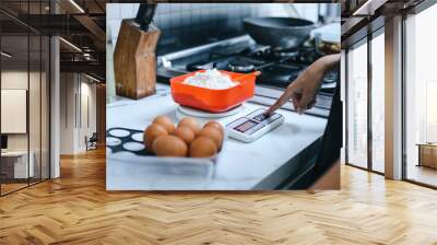 Hand weighing flour for baking on digital scales at the kitchen Wall mural