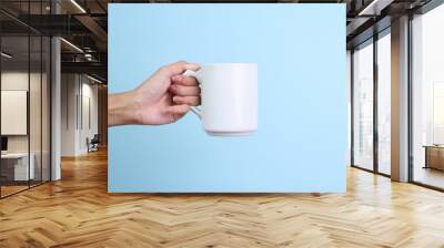 Hands Holding White Ceramic Mug for Mockup Isolated on Blue Background Wall mural